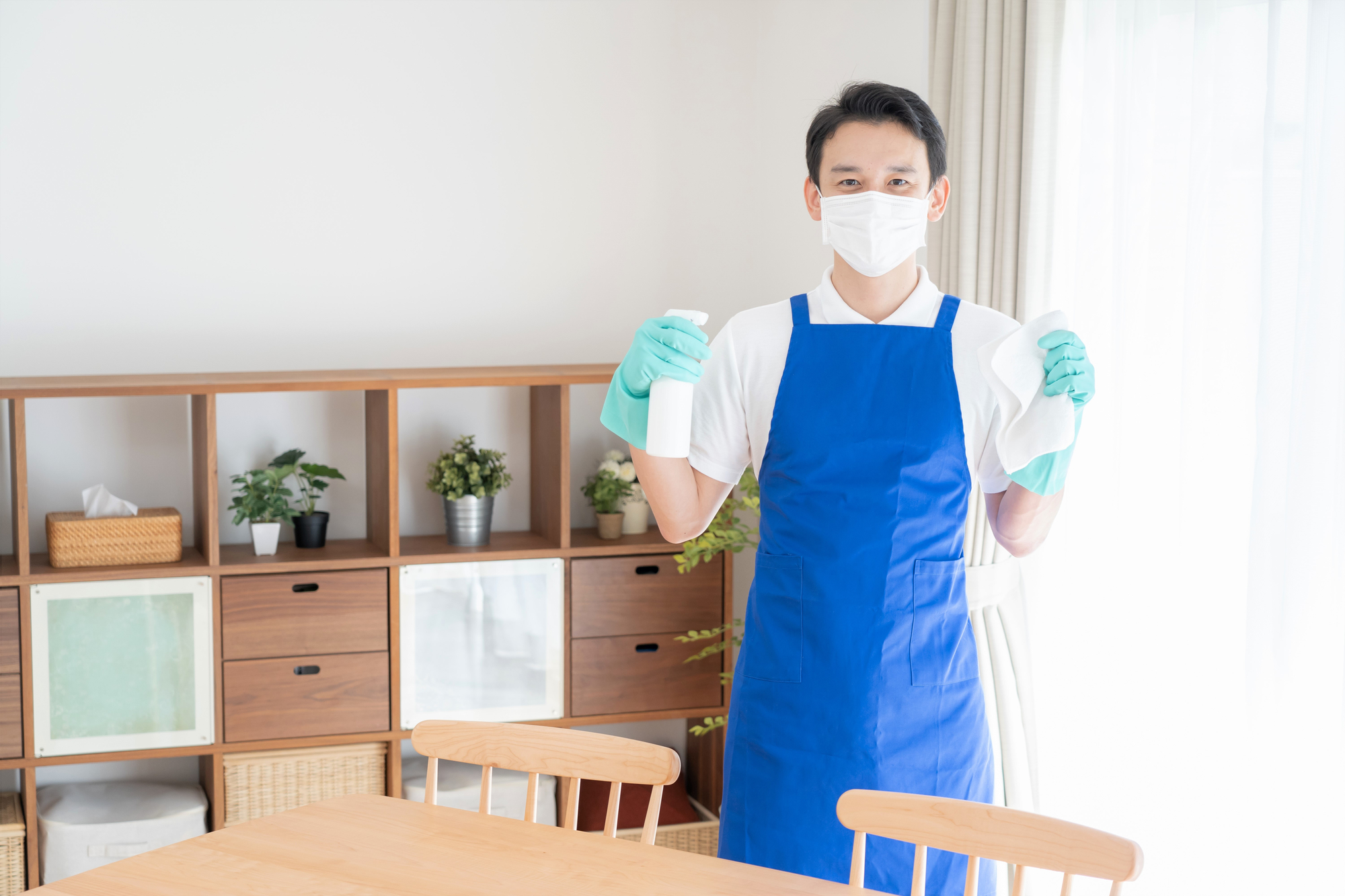 A Person Wearing a Mask and Gloves Holding a Spray Bottle